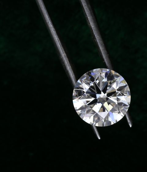 White diamond gemstone held in tweezers