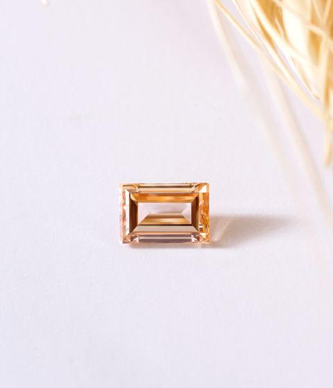 Yellow faceted gemstone on a white surface
