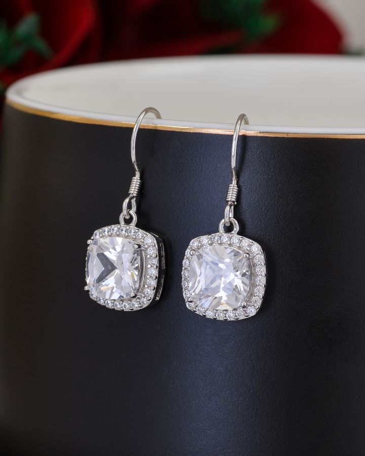 Sapphire stud earrings displayed on a natural wooden base